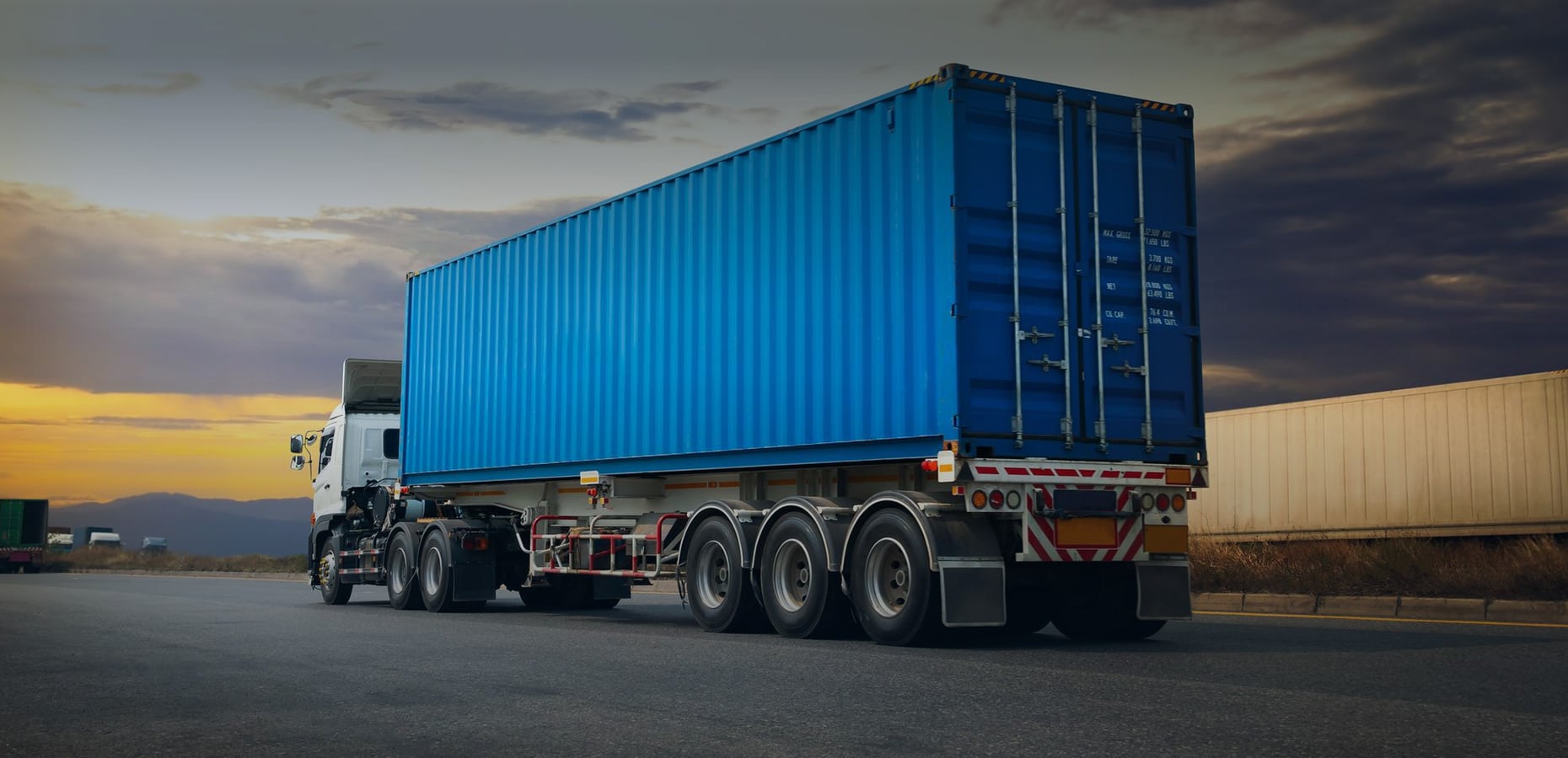 Modern container truck on an intercity highway at dusk